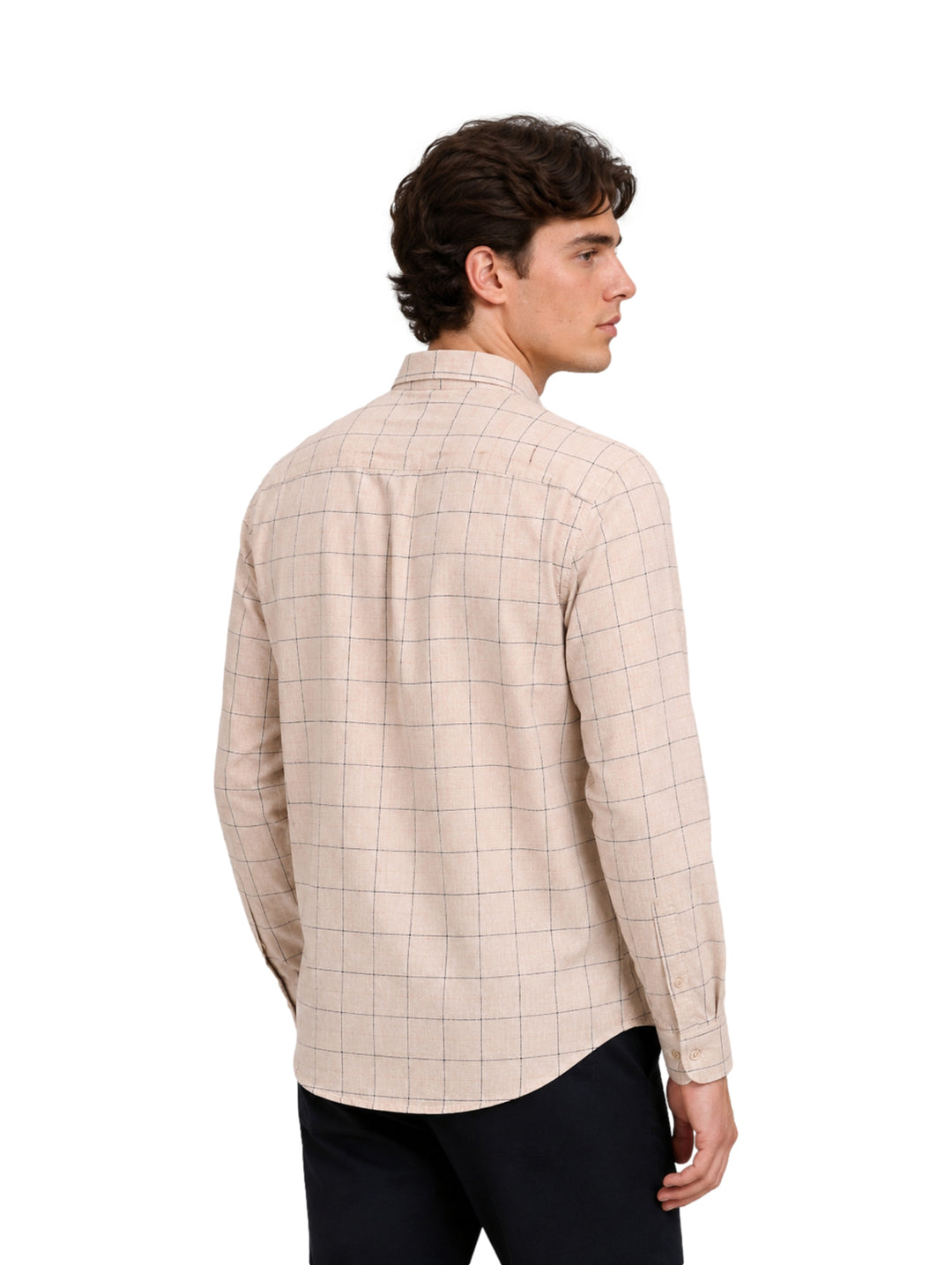 Hombre vistiendo camisa beige de manga larga con estampado de cuadros negros.