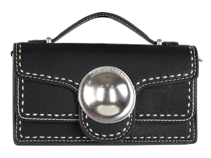 Bolso negro rectangular con costuras blancas y un adorno circular plateado central.