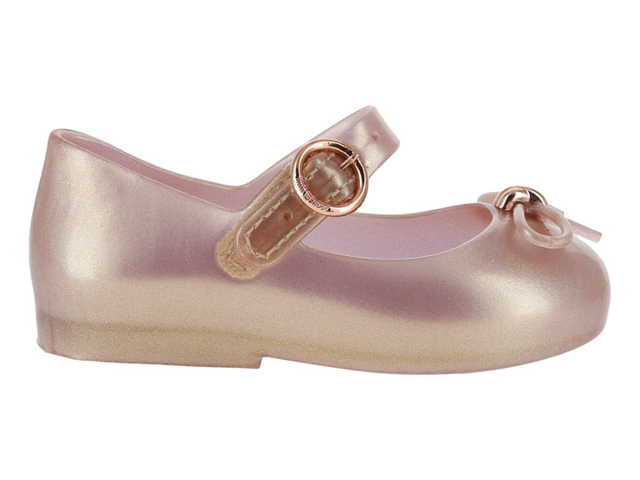 Zapato infantil Mary Jane de color rosa perlado con correa y moño decorativo.
