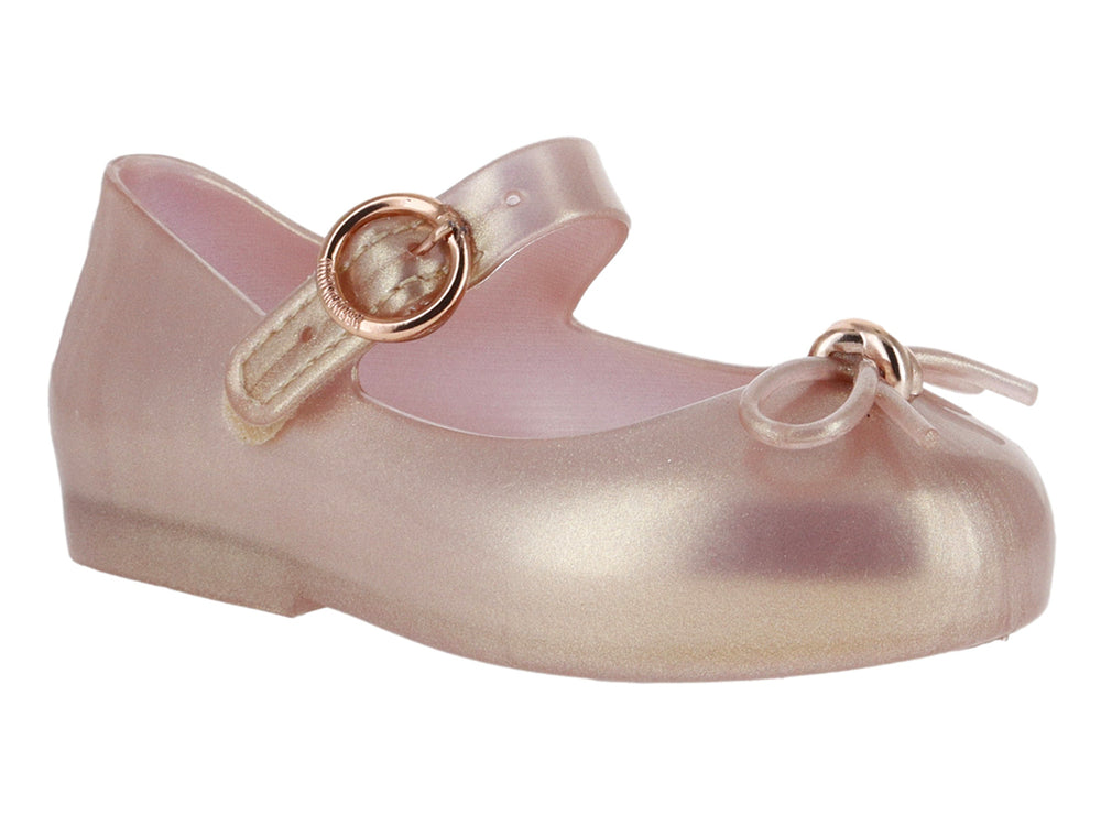 Zapato infantil Mary Jane de color rosa perlado con correa y moño decorativo.