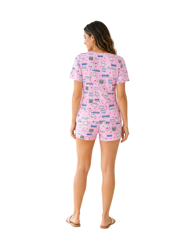 Mujer vistiendo pijama de dos piezas color rosa con estampado de tazas de café.