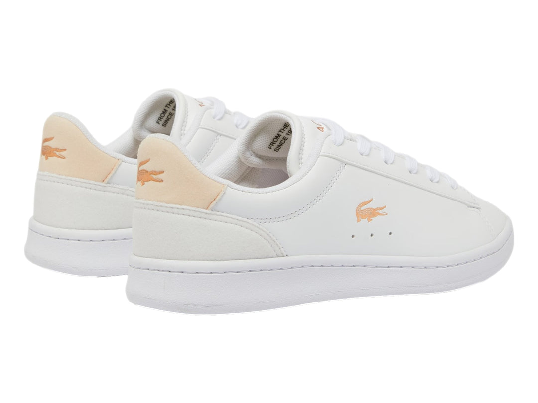 Tenis Lacoste blancos con detalles en rosa claro y logotipo del cocodrilo en el lateral.