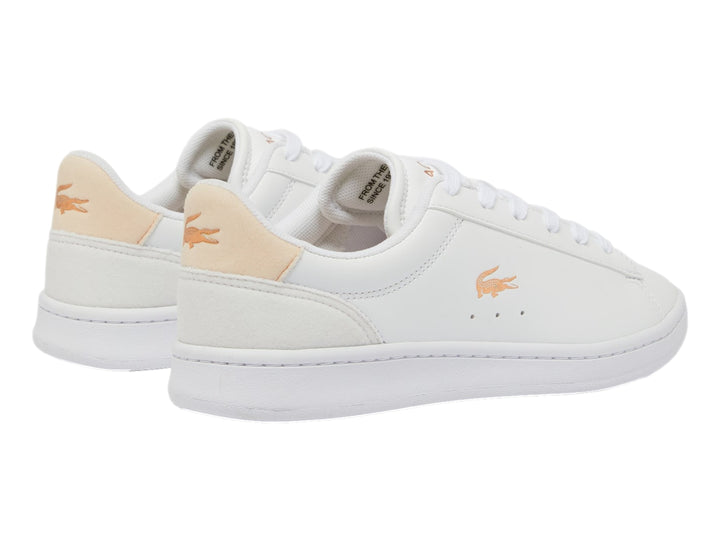 Tenis Lacoste blancos con detalles en rosa claro y logotipo del cocodrilo en el lateral.