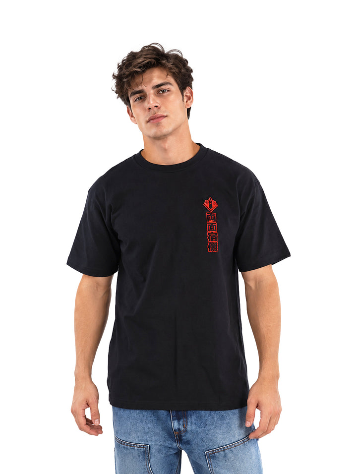 Hombre vistiendo playera negra de manga corta con letras rojas en el pecho y jeans azules.