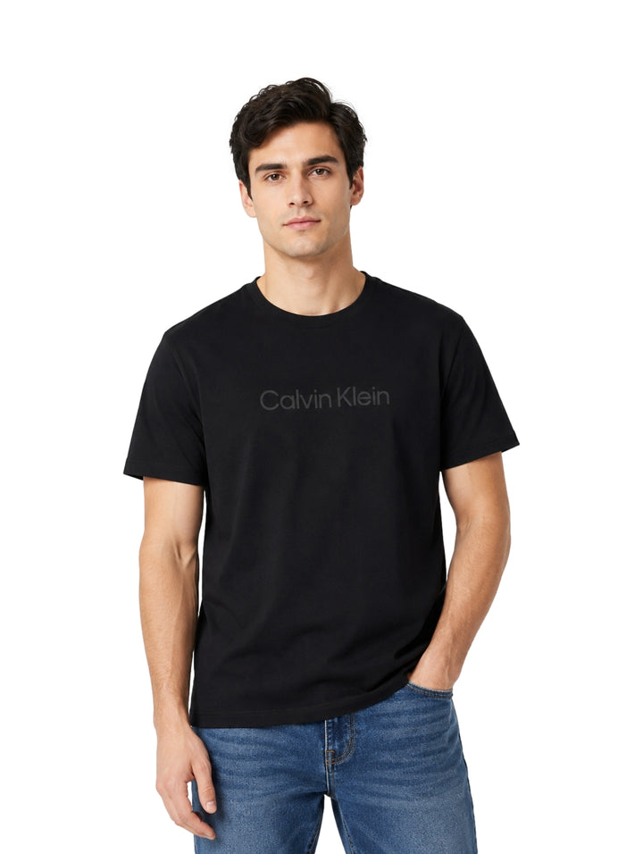 Hombre vistiendo playera negra de manga corta marca Calvin Klein con logo frontal.