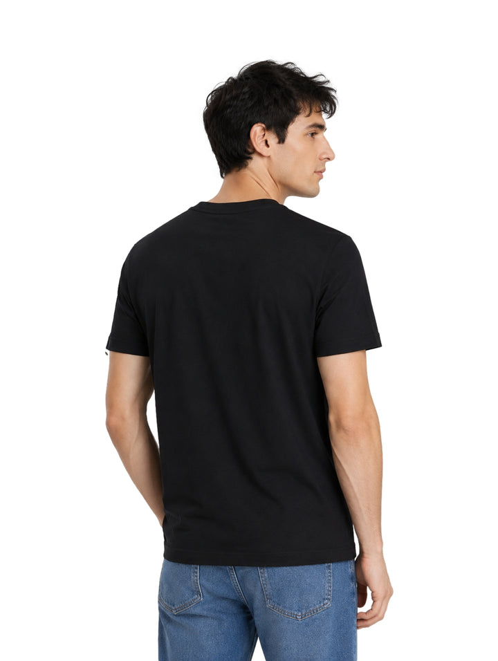 Hombre vistiendo una playera negra de manga corta con el logo de Calvin Klein en el pecho.