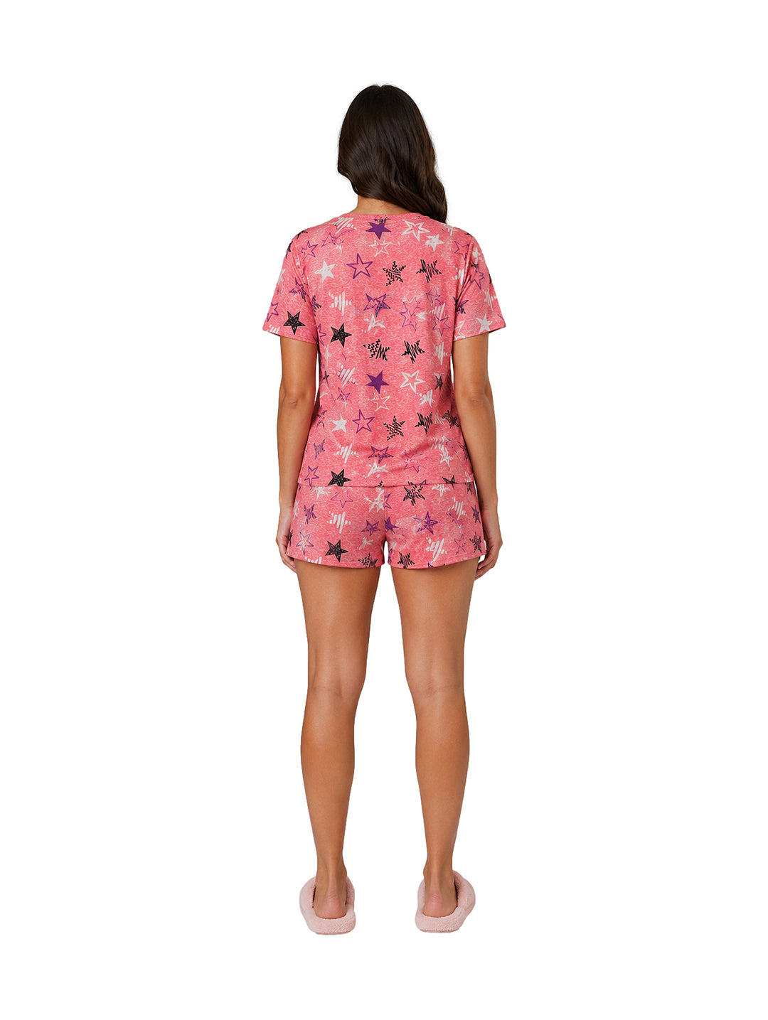 Mujer vistiendo pijama color coral de dos piezas con estampado de estrellas y pantuflas rosas.