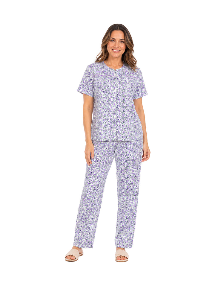Mujer vistiendo pijama morada con estampado blanco de dos piezas: camisa de manga corta y pantalón largo.