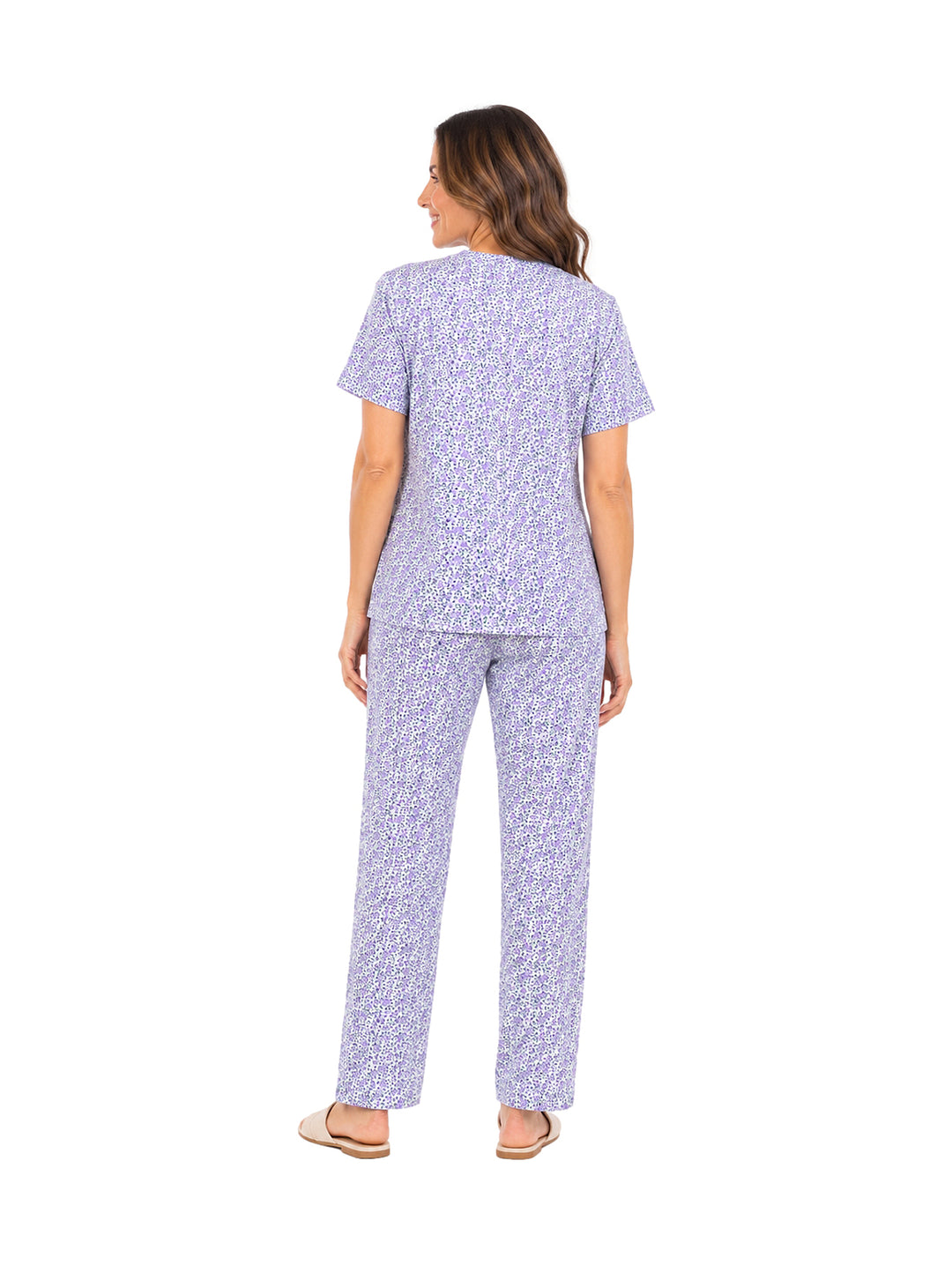Mujer vistiendo pijama morada con estampado blanco de dos piezas: camisa de manga corta y pantalón largo.