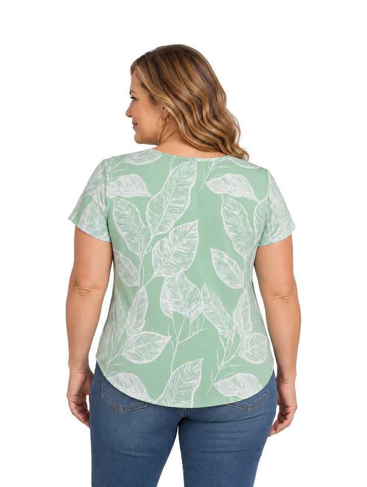 Mujer vistiendo blusa verde de manga corta con estampado de hojas blancas y cuello en V.