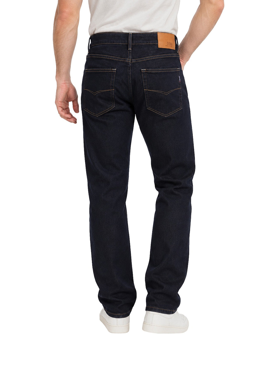 Hombre vistiendo jeans OGGI color dark indigo de corte recto con costuras naranjas y tenis blancos.
