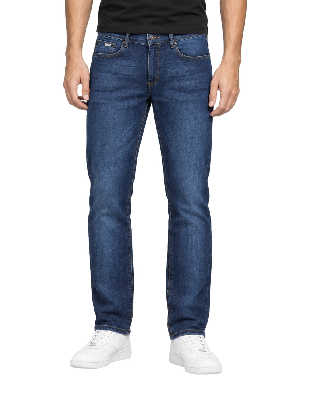 Hombre vistiendo jeans slim fit Lee color azul stone con tenis blancos sobre fondo blanco.