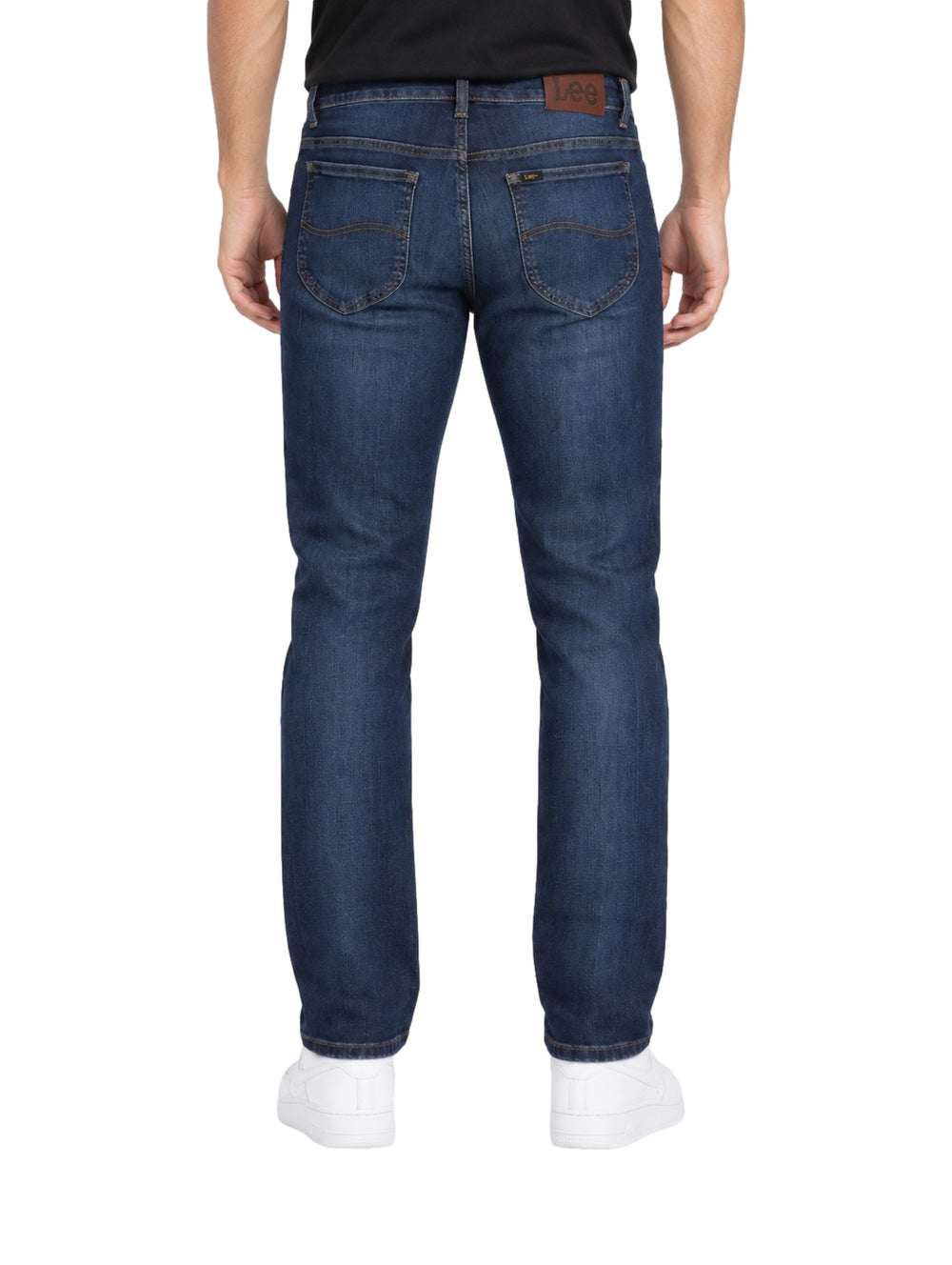 Hombre vistiendo jeans slim fit Lee color azul stone con tenis blancos sobre fondo blanco.