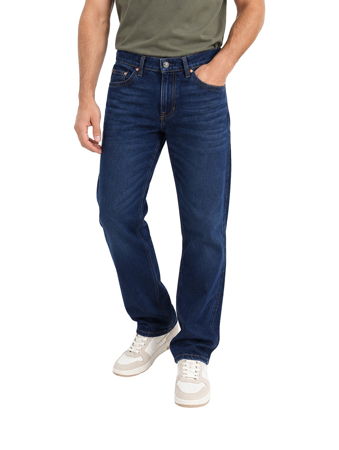 Hombre vistiendo jeans slim boot retro Wrangler en color azul oscuro con tenis blancos.