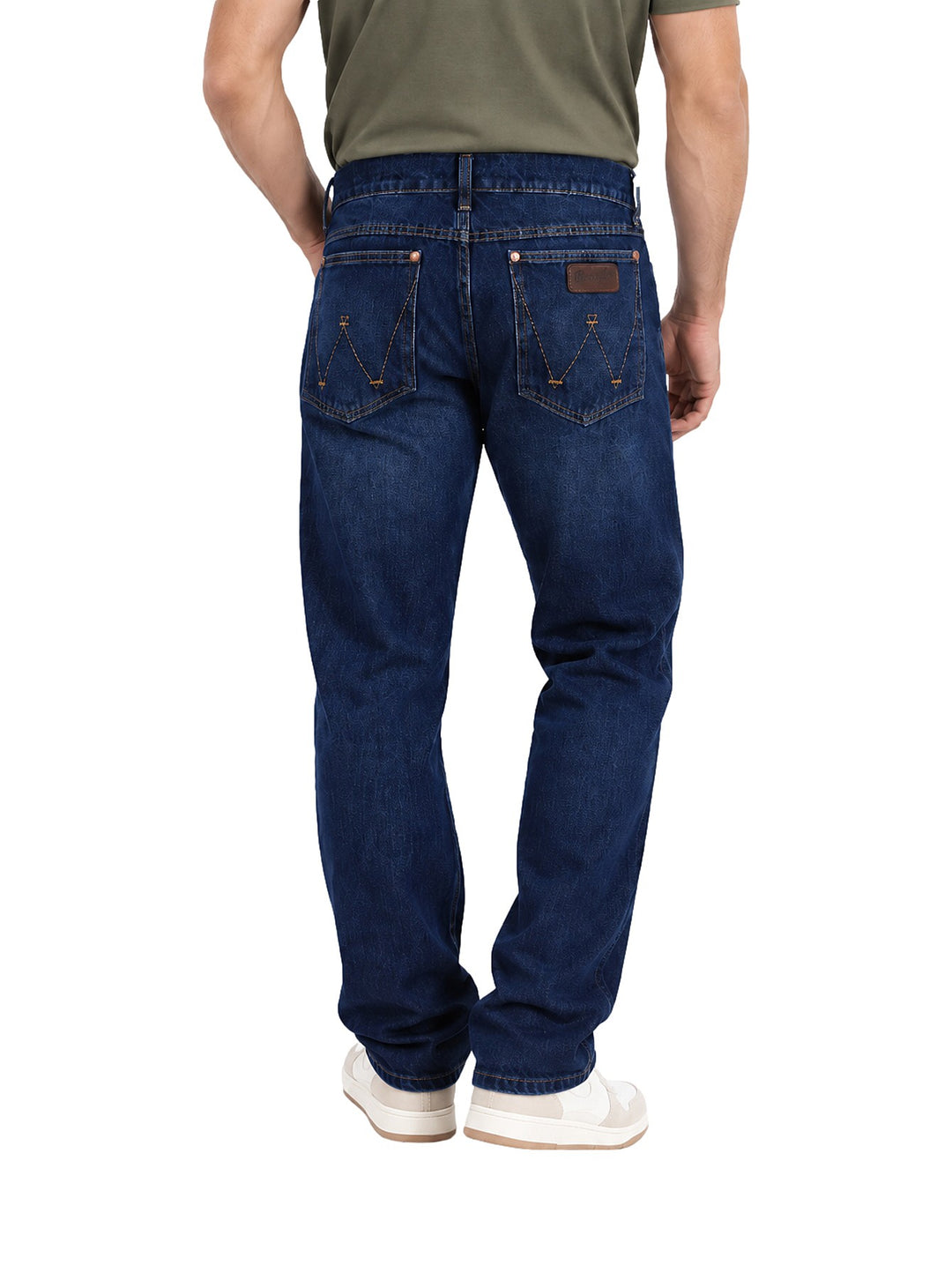 Hombre vistiendo jeans slim boot retro Wrangler en color azul oscuro con tenis blancos.