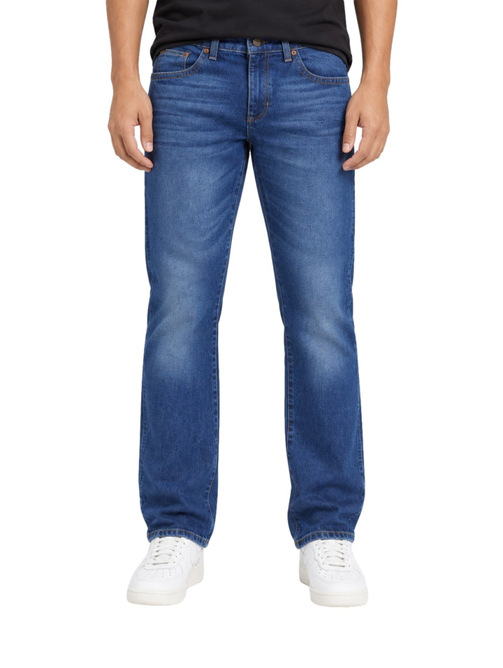Hombre vistiendo jeans slim boot retro Wrangler en color azul con calzado blanco.