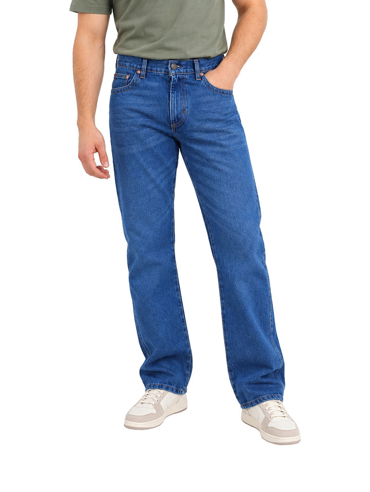 Hombre vistiendo jeans Wrangler color indigo de corte slim boot retro con calzado blanco.