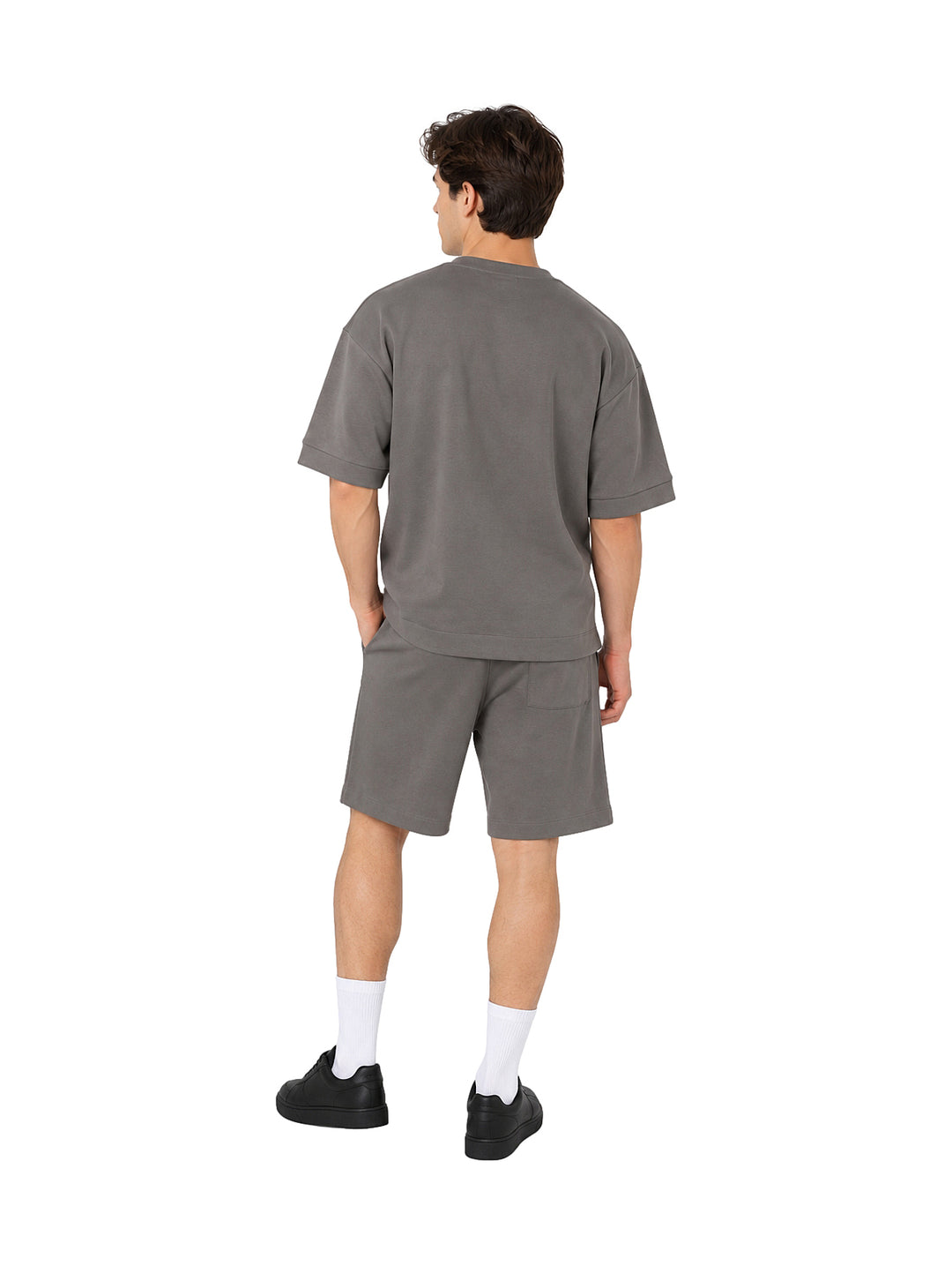 Hombre vistiendo un conjunto de camiseta y shorts color gris de estilo casual y holgado.
