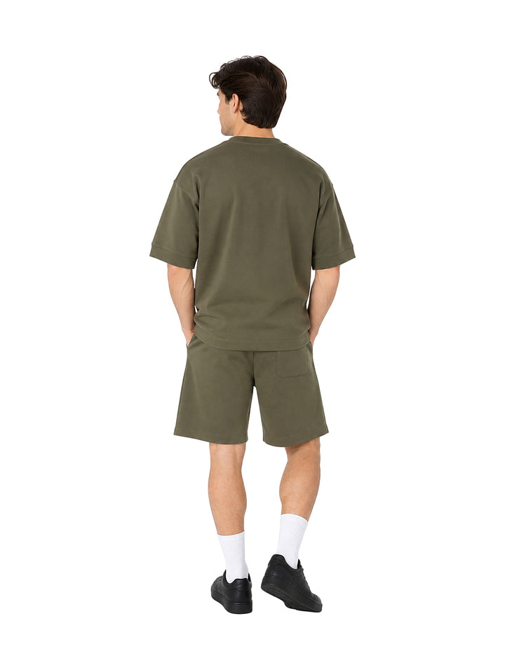 Hombre vistiendo un conjunto de camiseta y shorts color olivo.