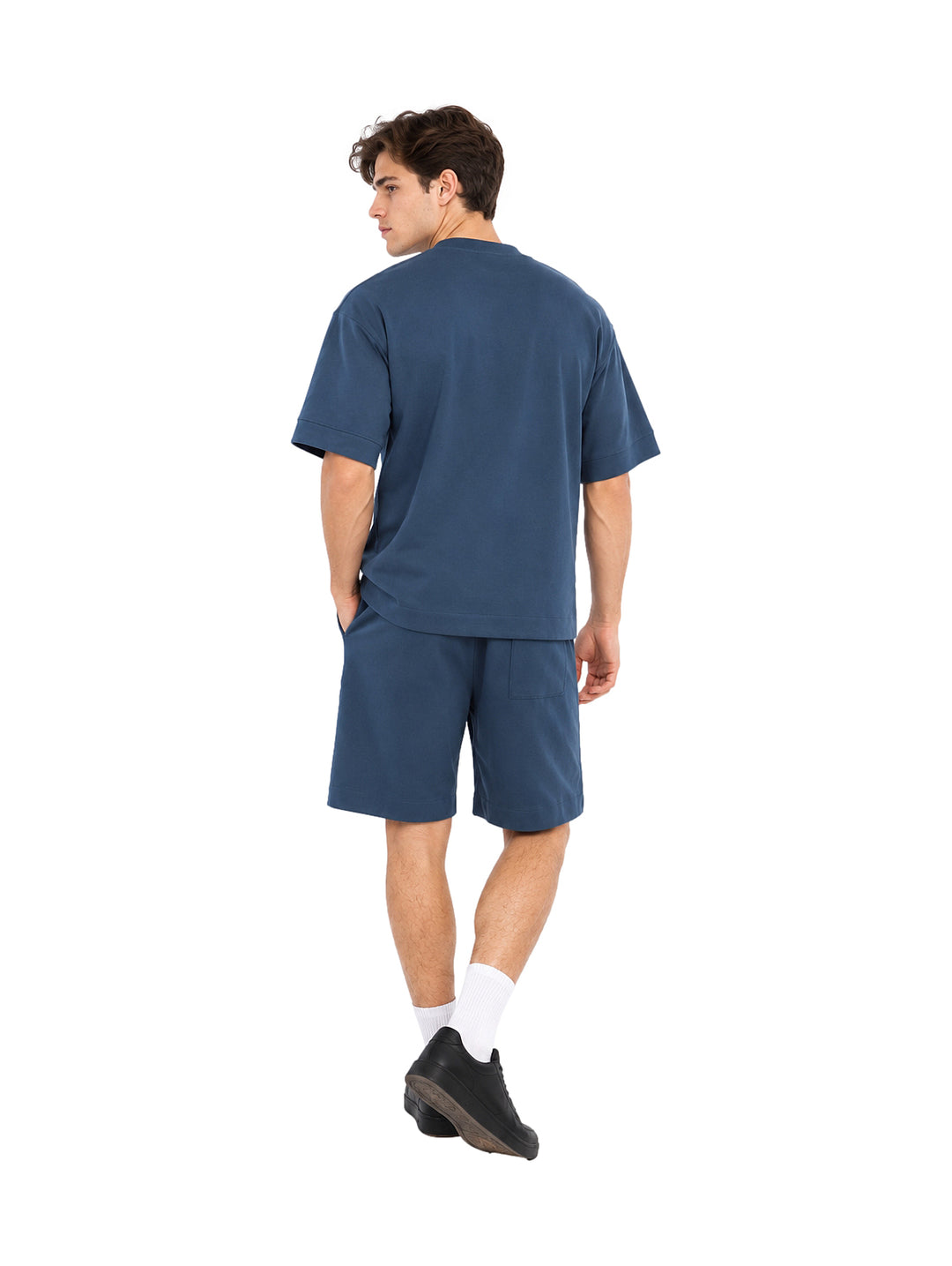 Hombre vistiendo un conjunto de camiseta y shorts color teal.