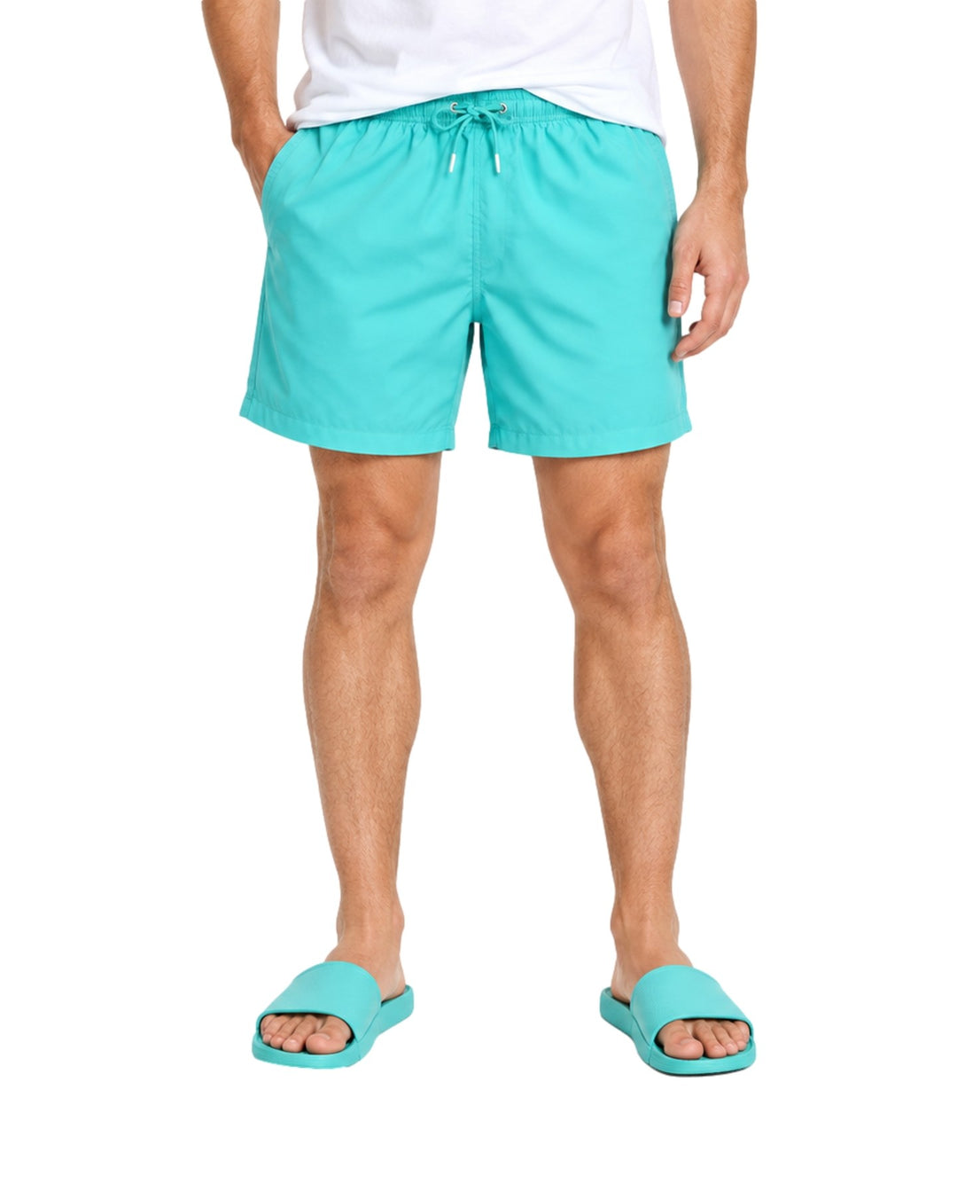 Hombre vistiendo un traje de baño corto color verde menta con cordón ajustable y sandalias a juego.