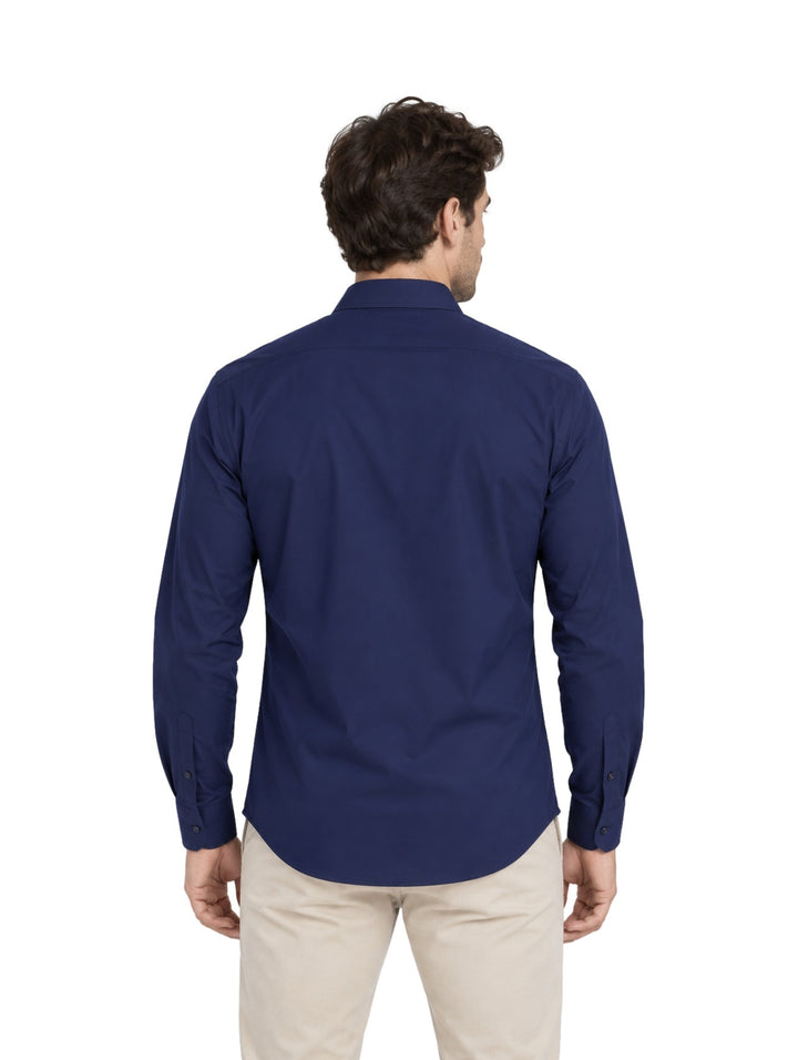 Hombre vistiendo una camisa American Fly de color marino con pantalones beige sobre fondo blanco.