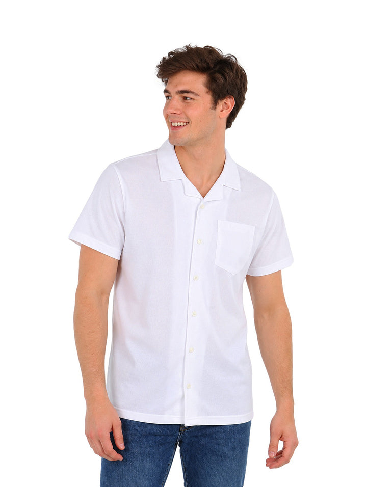 Hombre vistiendo una camisa American Fly de color blanco, manga corta y cuello, combinada con jeans azules.