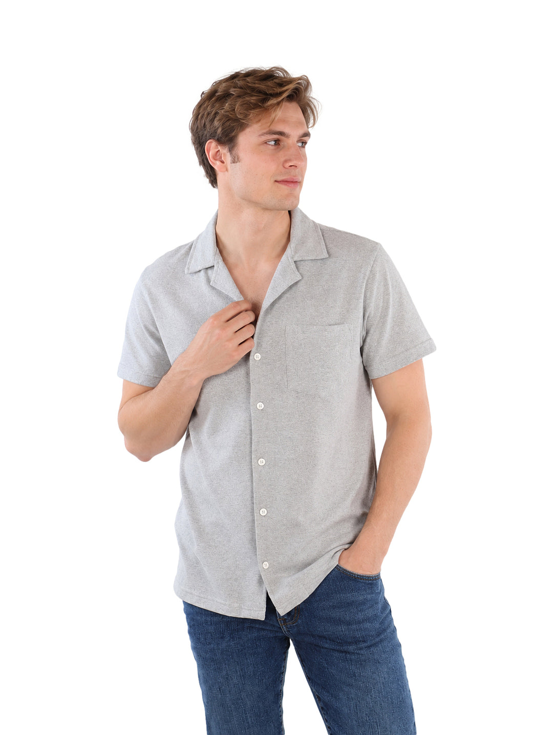 Hombre vistiendo una camisa gris de manga corta con botones y jeans azules sobre fondo blanco.