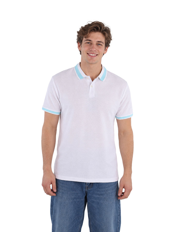 Hombre vistiendo playera polo blanca con detalles en color celeste en el cuello y mangas.