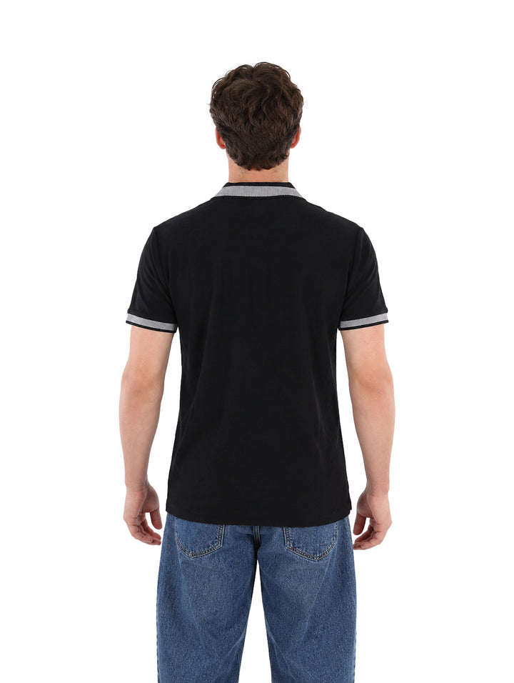 Hombre vistiendo playera polo color negro con detalles grises en el cuello y los bordes de las mangas.