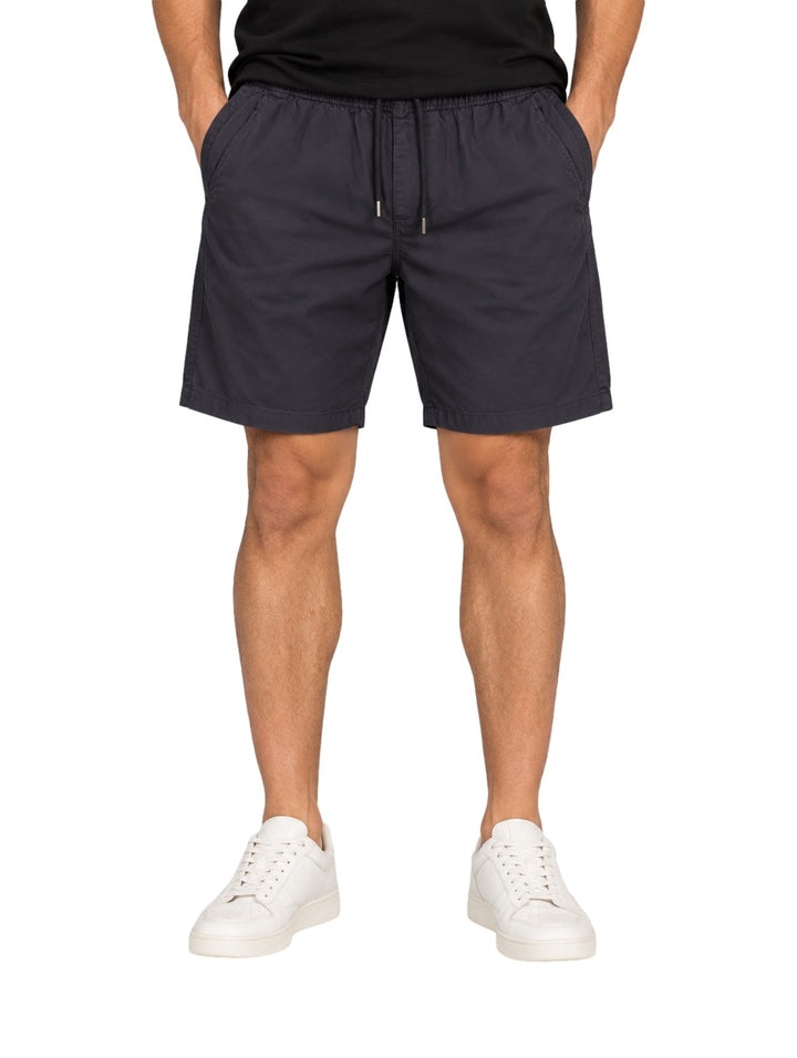 Hombre vistiendo bermuda American Fly color marino con cintura elástica y cordón, combinada con tenis blancos.