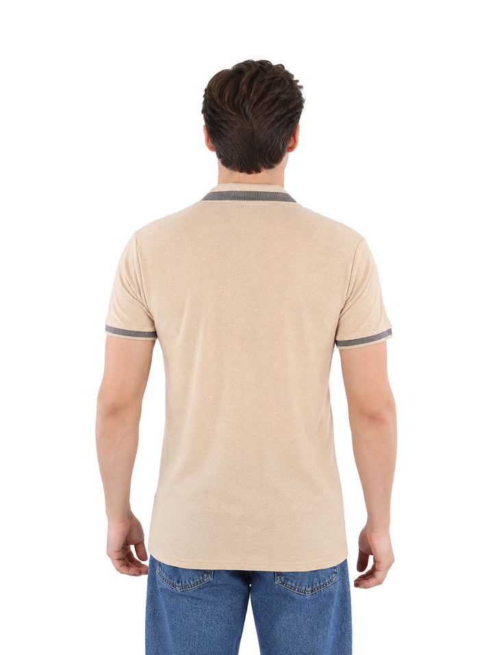 Hombre vistiendo playera polo color beige con detalles grises en el cuello y los puños.