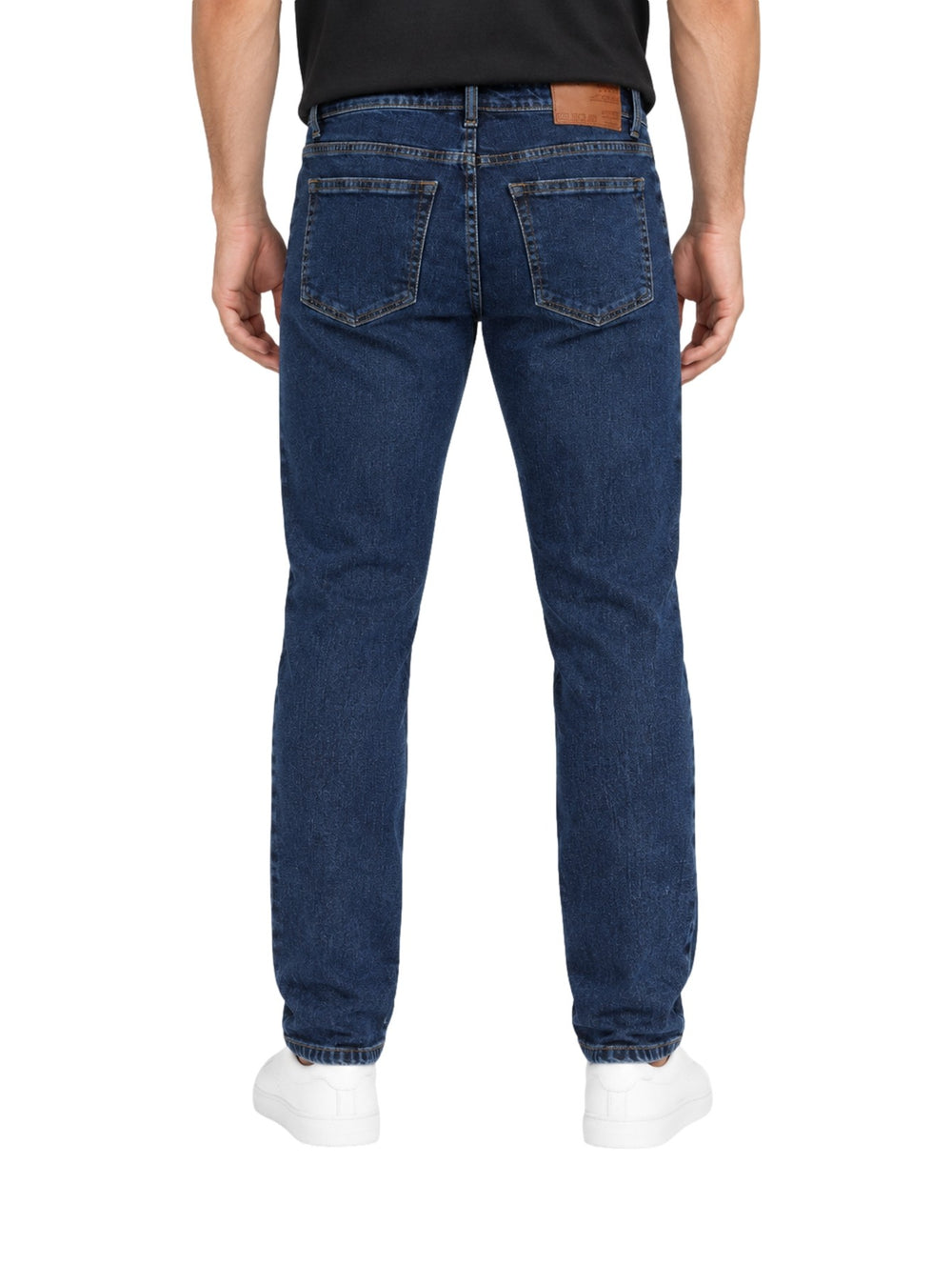 Hombre vistiendo jeans slim fit color azul oscuro de la marca Collor's Couture con tenis blancos.