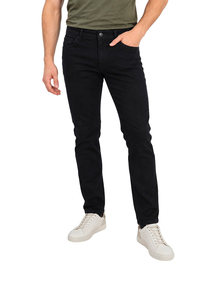 Hombre vistiendo jeans slim fit rectos de color negro con calzado blanco sobre fondo blanco.