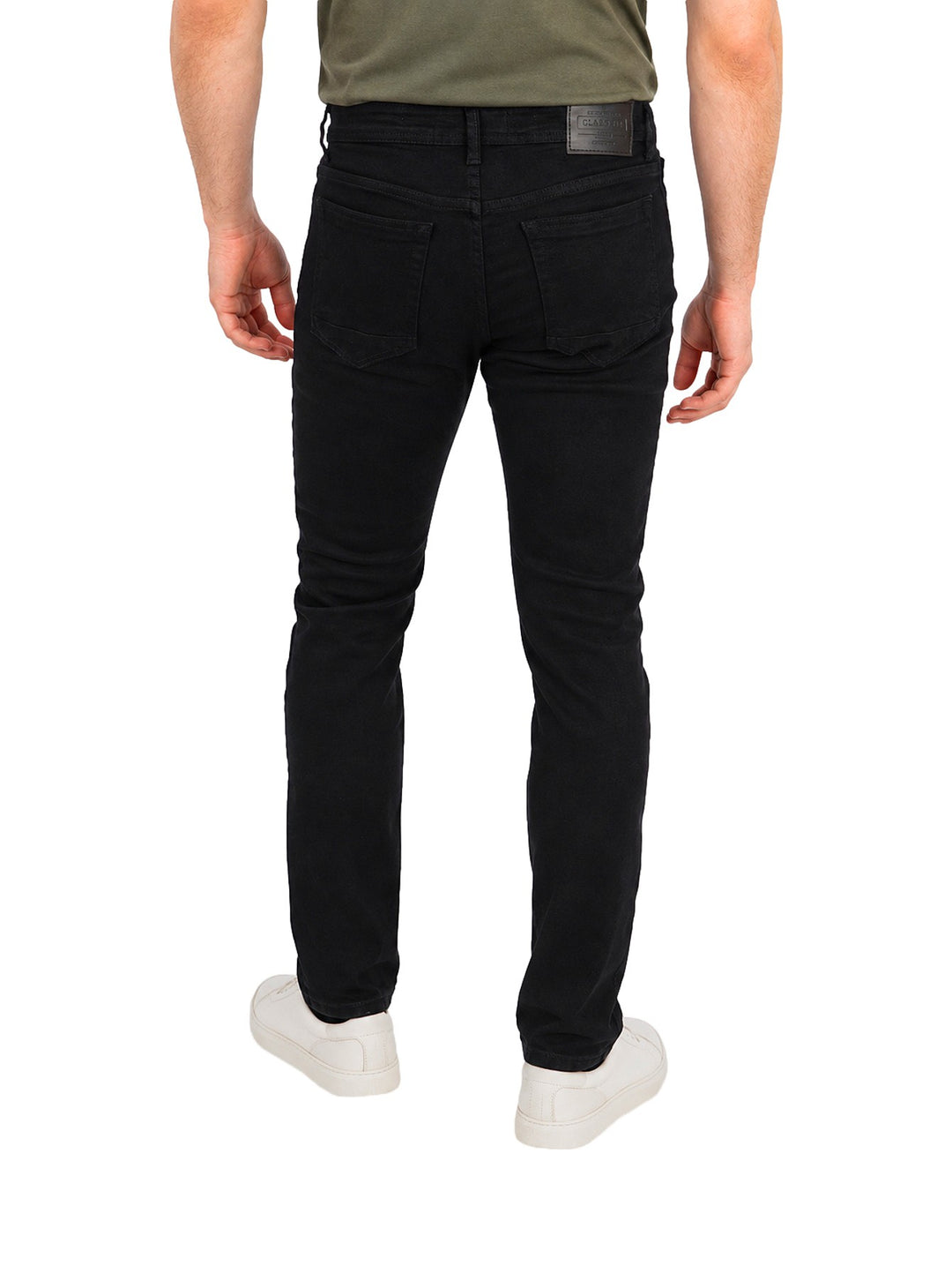 Hombre vistiendo jeans slim fit rectos de color negro con calzado blanco sobre fondo blanco.