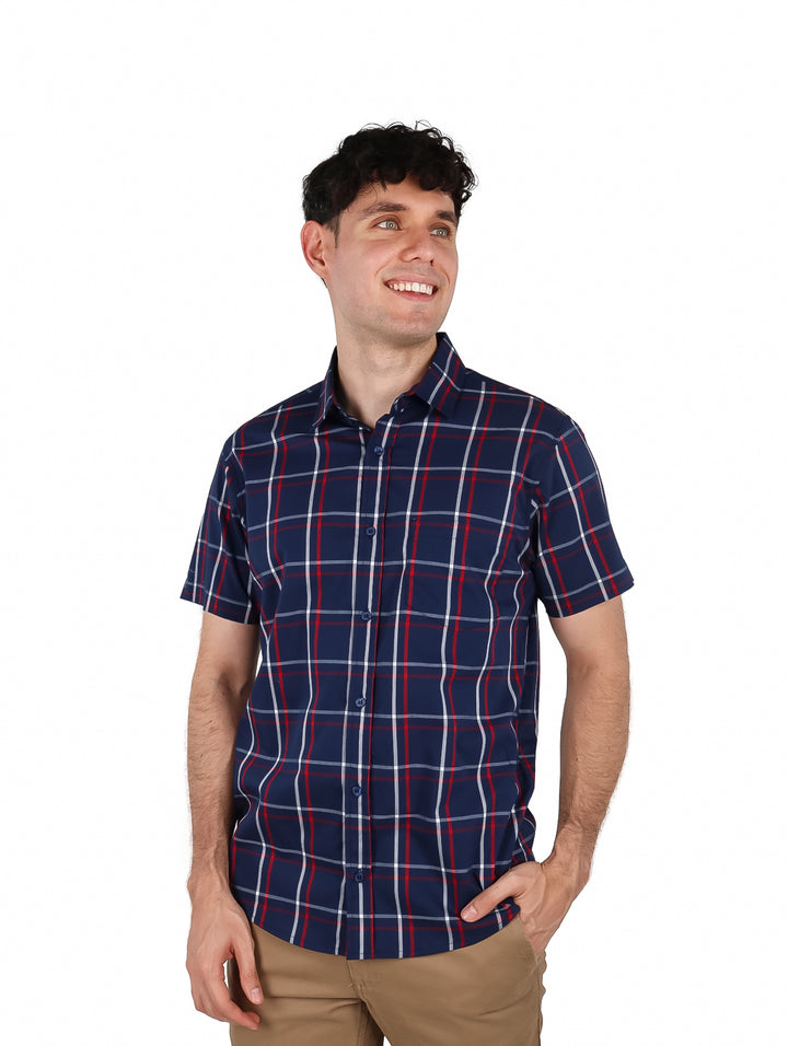 Hombre vistiendo camisa de manga corta color marino con patrón de cuadros rojos y blancos.