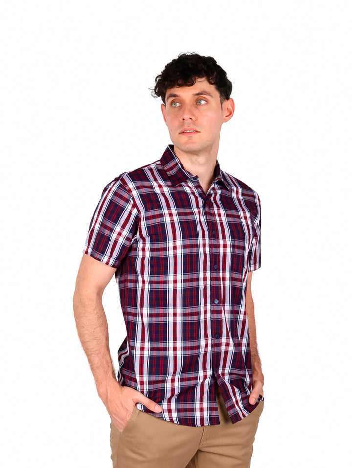 Hombre vistiendo camisa de manga corta con estampado de cuadros en colores rojo y marino.