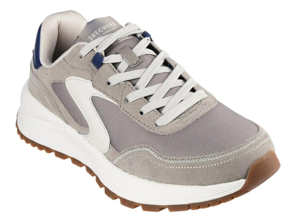 Tenis Skechers color gris natural con suela blanca y detalles en azul y café.