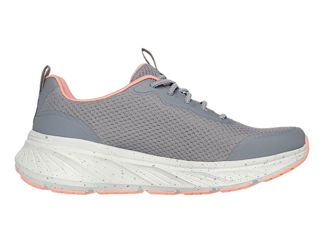 Tenis deportivos Skechers en color gris con detalles en coral y suela blanca moteada para mujer.