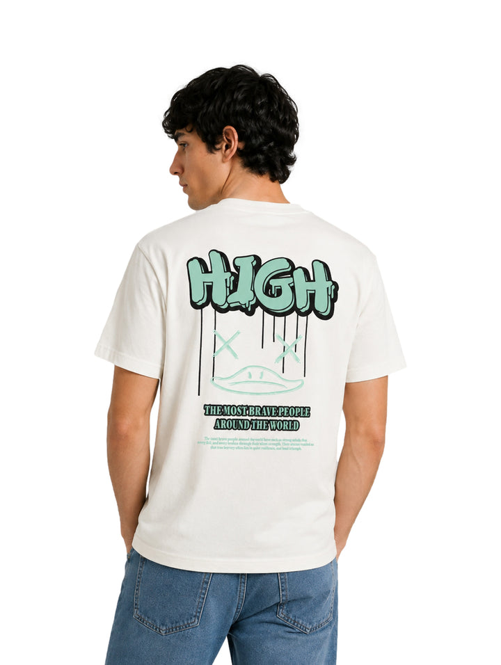 Hombre usando playera blanca de manga corta con estampado pequeño en el centro y jeans azules.