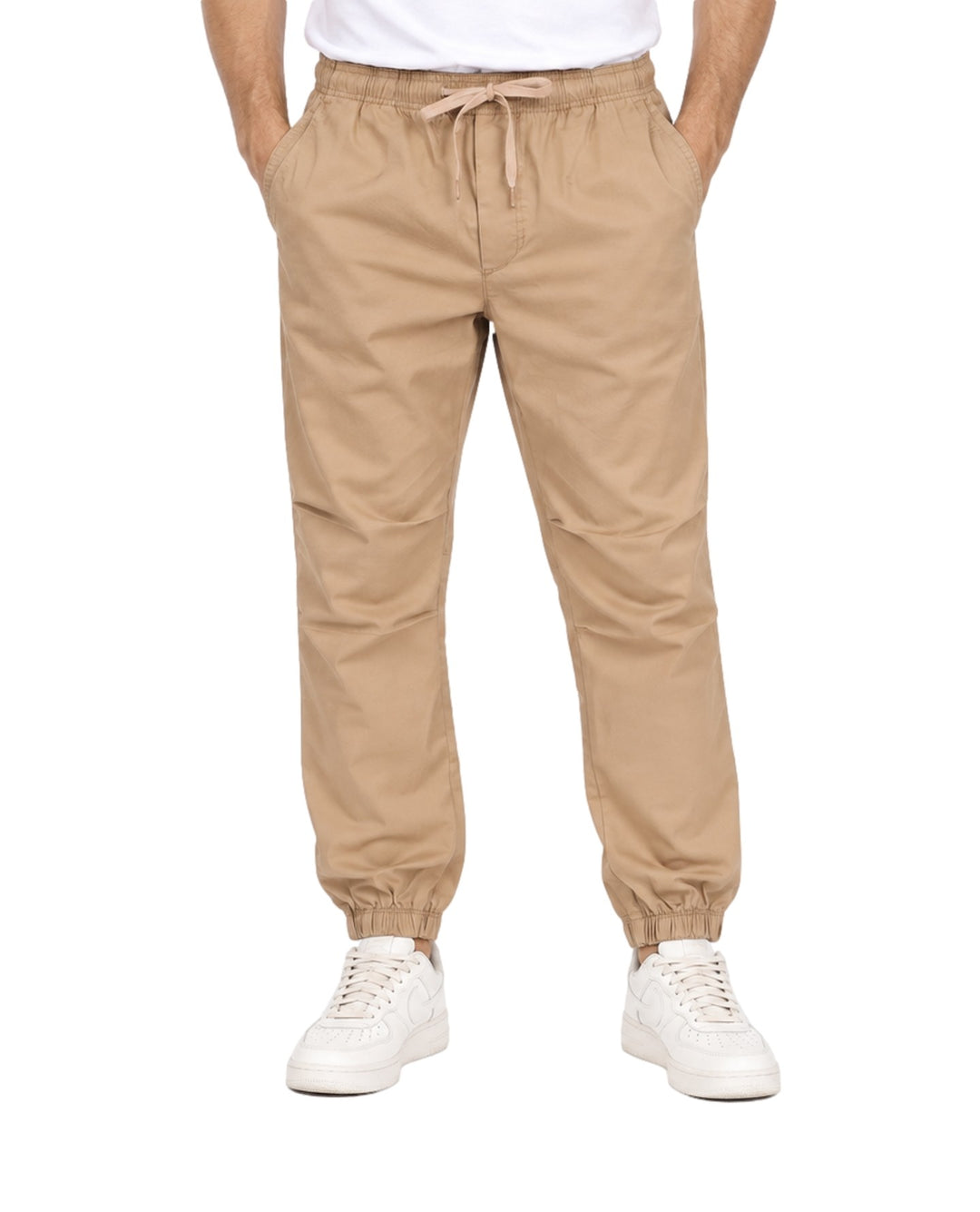 Hombre vistiendo pantalones jogger color khaki con cintura y tobillos elásticos y tenis blancos.