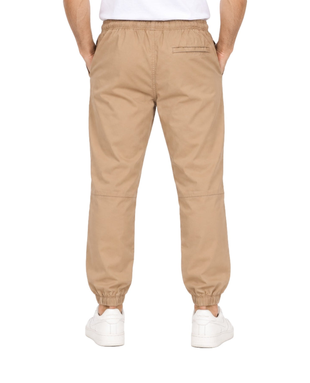 Hombre vistiendo pantalones jogger color khaki con cintura y tobillos elásticos y tenis blancos.