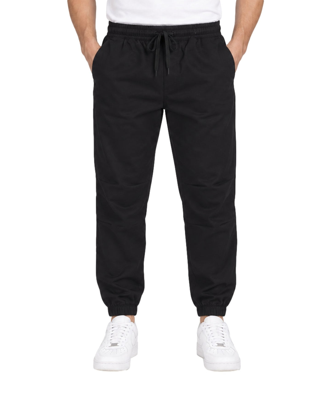 Hombre vistiendo pantalón jogger deportivo color negro con cintura elástica y calzado blanco.