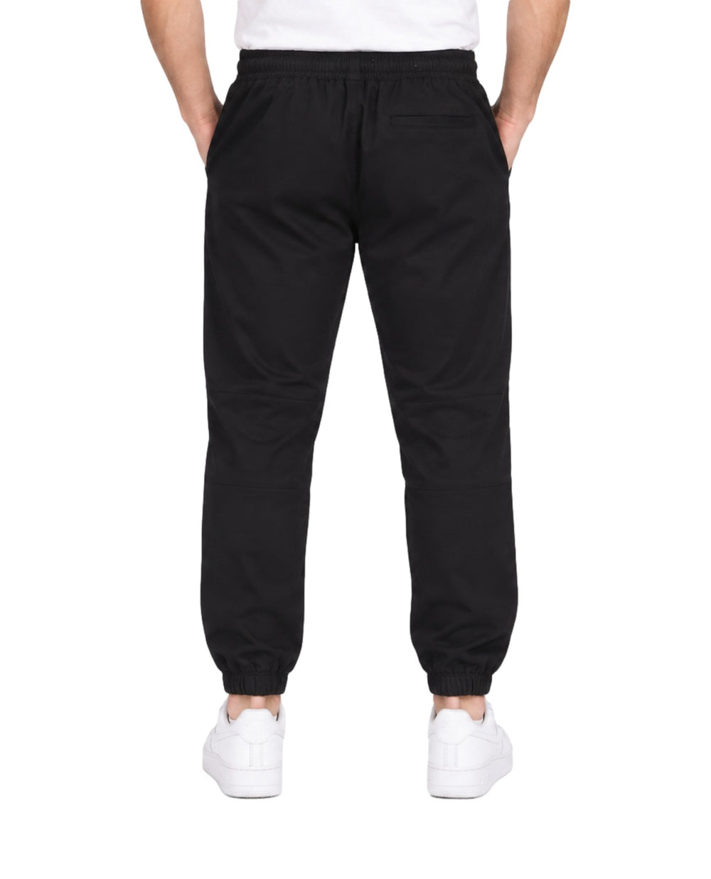 Hombre vistiendo pantalón jogger deportivo color negro con cintura elástica y calzado blanco.
