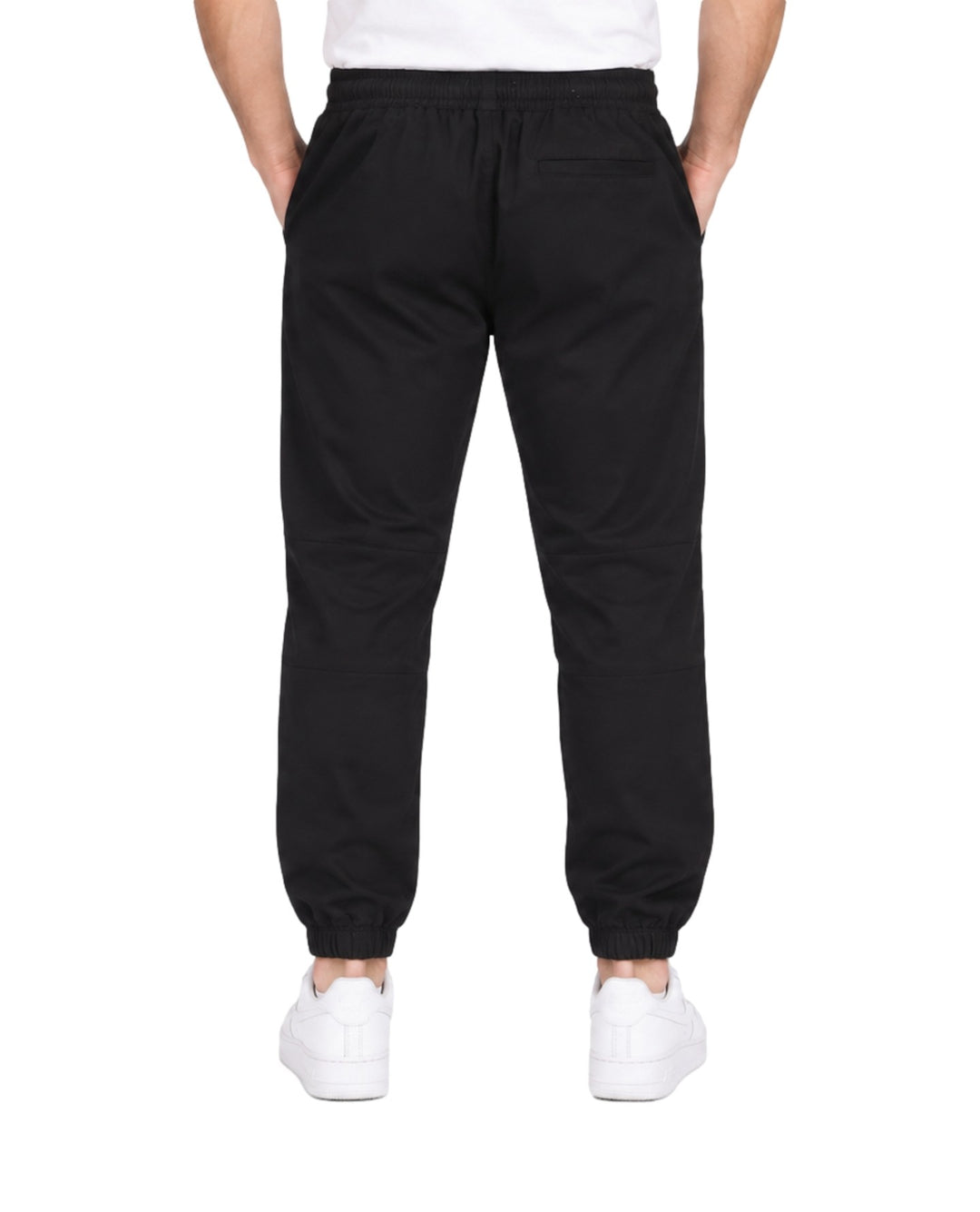 Hombre vistiendo pantalón jogger deportivo color negro con cintura elástica y calzado blanco.