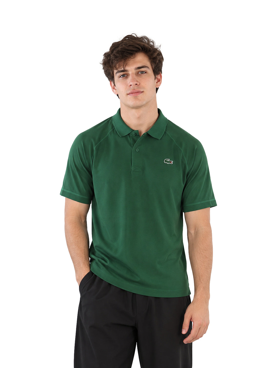 Hombre usando playera polo Lacoste color verde y pantalones negros.