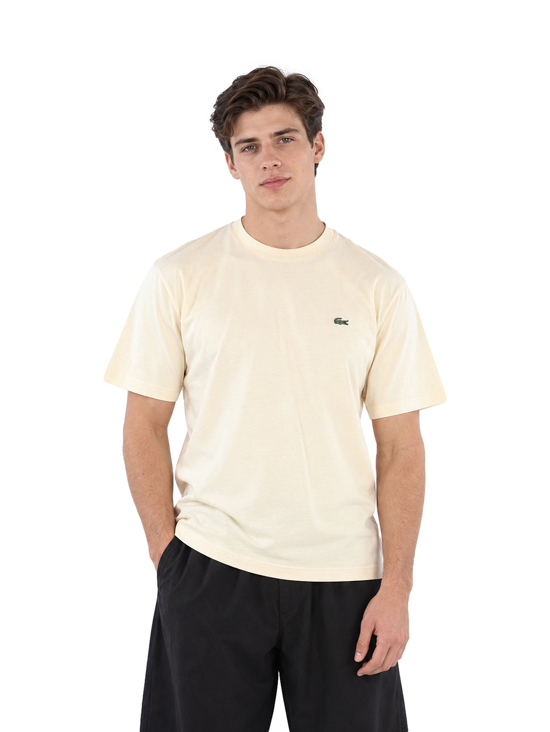 Hombre vistiendo una playera Lacoste color beige de manga corta y cuello redondo.
