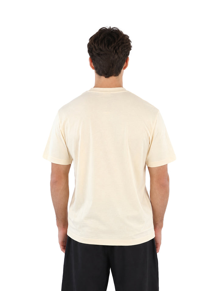 Hombre vistiendo una playera Lacoste color beige de manga corta y cuello redondo.