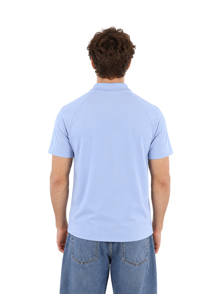 Hombre vistiendo una playera polo Lacoste de color azul claro con cuello y botones.