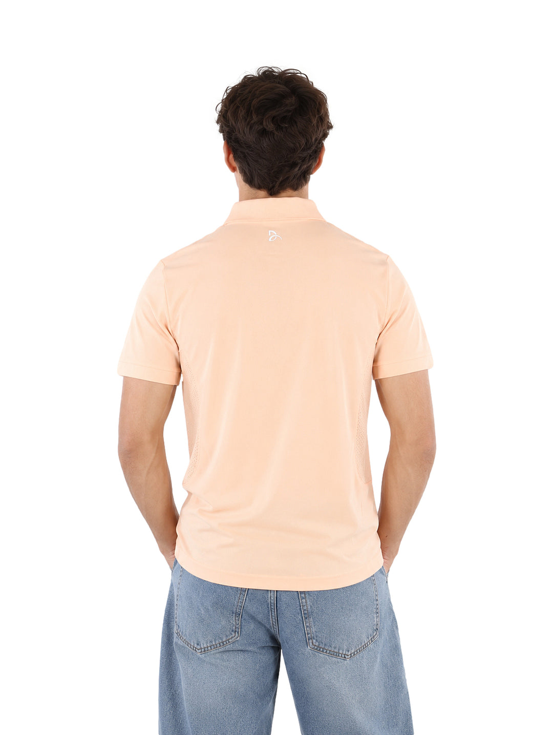 Hombre vistiendo una playera polo Lacoste de color rosa claro y pantalones de mezclilla azules.